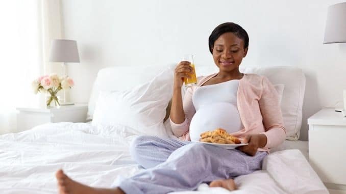 Happy pregnant woman with croissant buns at home
